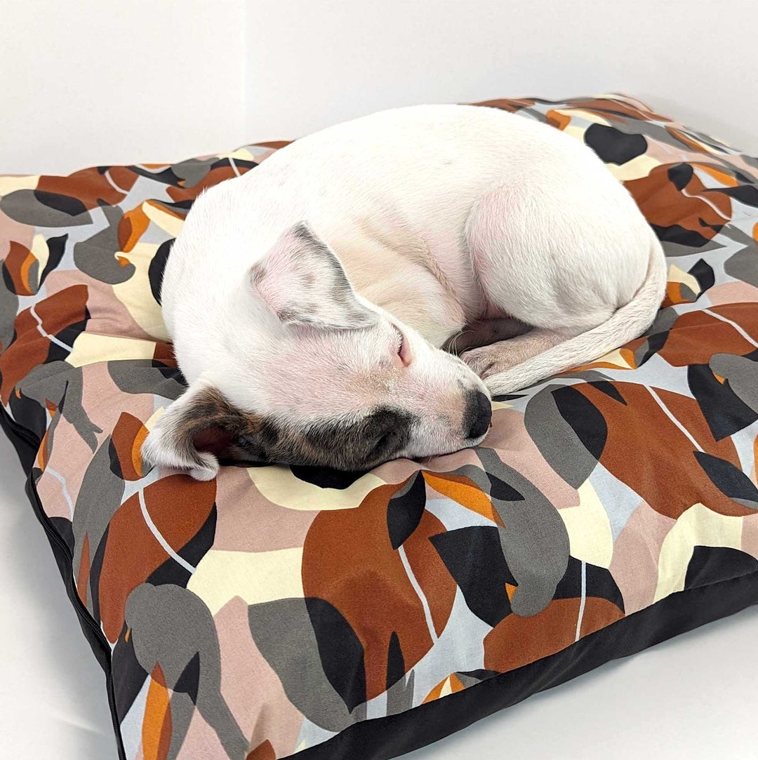 Chiot dormant profondément et confortablement sur un coussin coloré et tendance chien de la marque Goofy Goldens. 