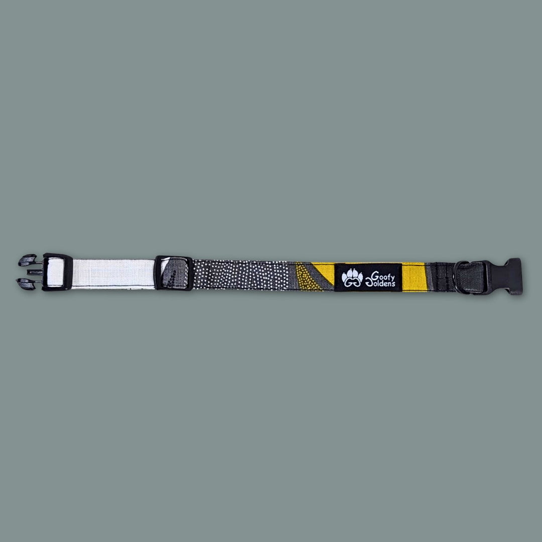 Joli collier chien tissu de la marque Goofy Goldens. Le collier est présenté ouvert et à plat pour distinguer les motifs et couleurs noir jaune et gris.