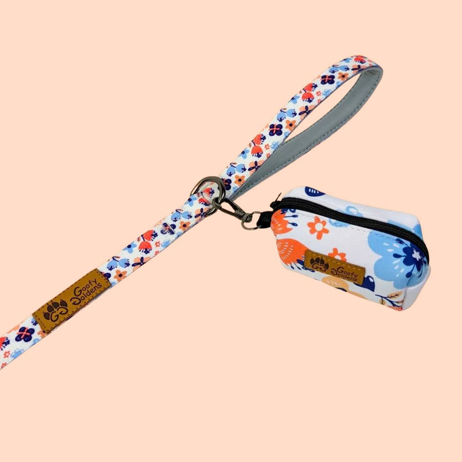 Distributeur fleuri de sacs à déjections pour chien aux tons bleu et orange accroché à la laisse