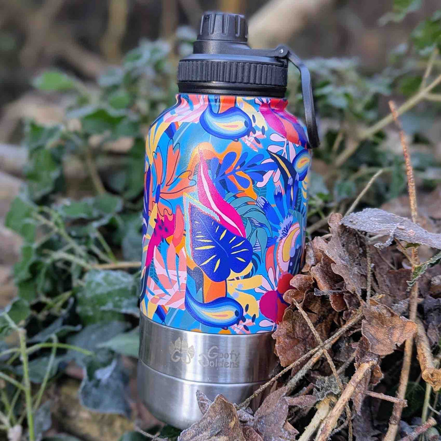 Gourde colorée 3-en-1 isotherme lagon, posée au milieu de branches et de feuilles.