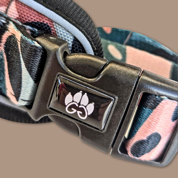 Gros plan sur la boucle au logo de Goofy-Goldens du harnais anti-traction Savane aux motifs de feuillages et de tâches de léopard.