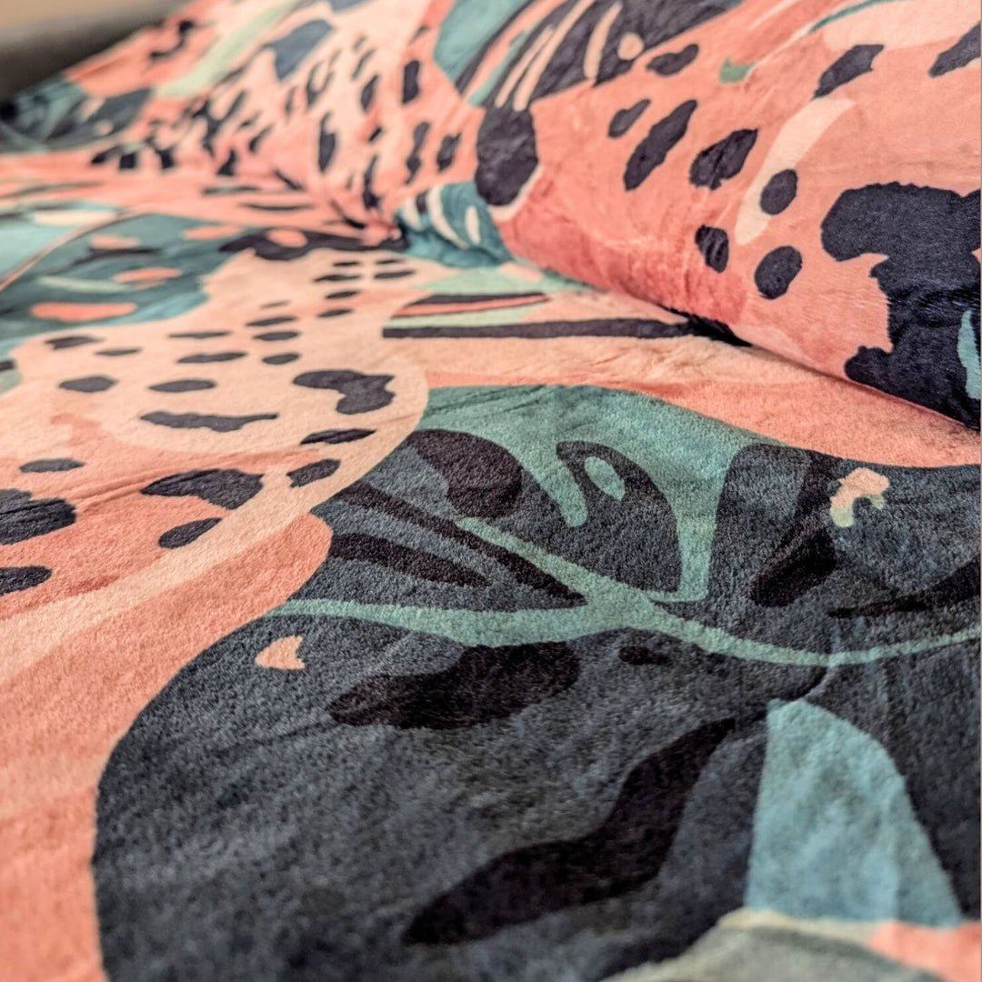 Plaid polaire 330gr aux mélanges de marron, vert et beige avec des motifs de feuillages et de tâches de léopard.