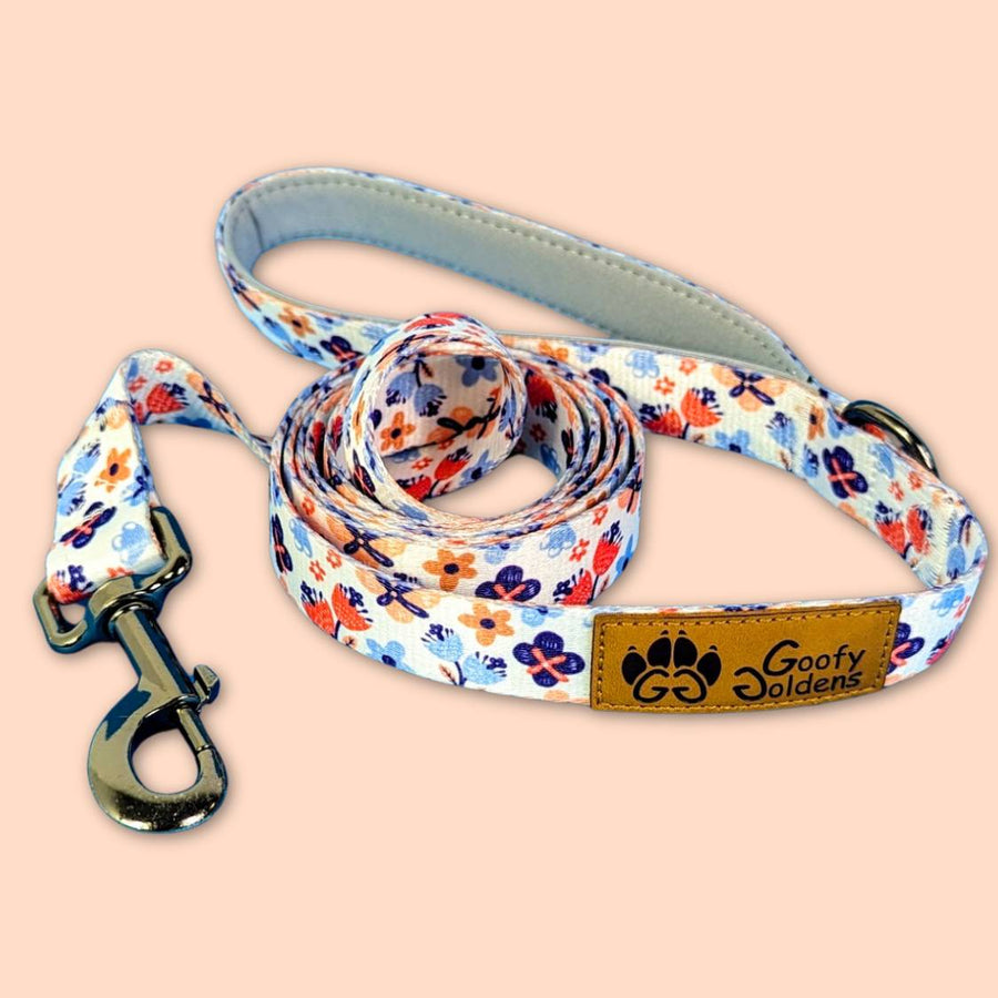 Laisse pour chien originale et stylée aux motifs fleuris dans des nuances d'orange et de bleu de la marque Goofy Goldens reconnaissable à son logo en forme de patte de chien.