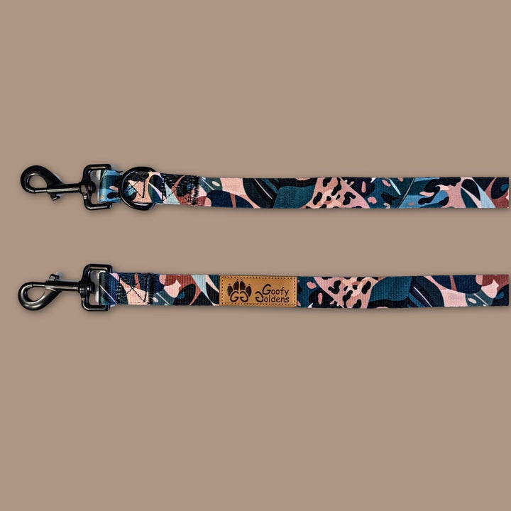 On aperçoit les deux mousquetons de la laisse Multiposition Savane, décorée de motifs feuillage et léopard aux couleurs de marron, beige et vert.