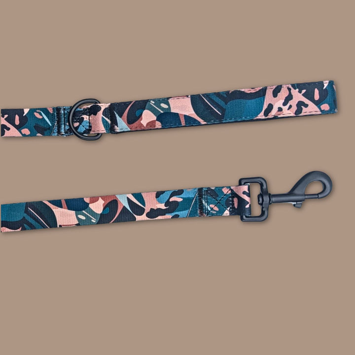 On aperçoit le mousqueton et l'anneau de la laisse Savane, décorée de motifs feuillage et léopard aux couleurs de marron, beige et vert.