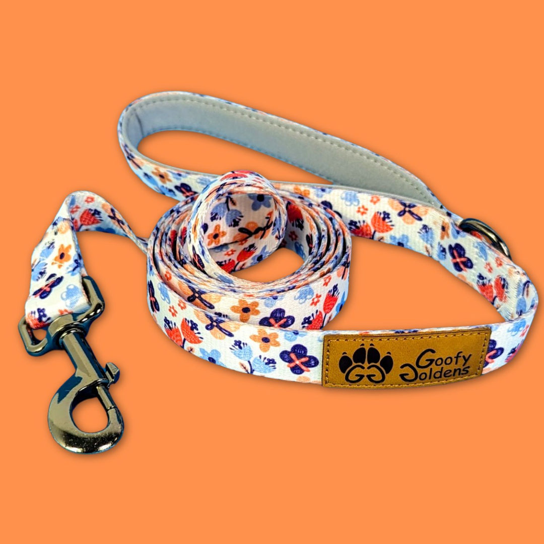 Laisse pour chien originale et stylée aux motifs fleuris dans des nuances d'orange et de bleu de la marque Goofy Goldens reconnaissable à son logo en forme de patte de chien.