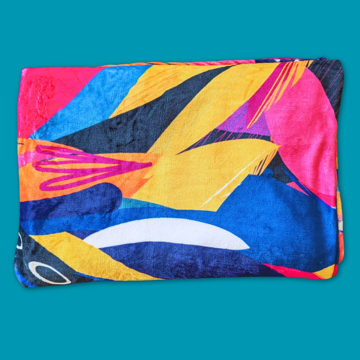 Zoom sur le plaid de la gamme Panache aux dessins abstraits de plumes jaune, orange, bleu, violet et fuchsia.