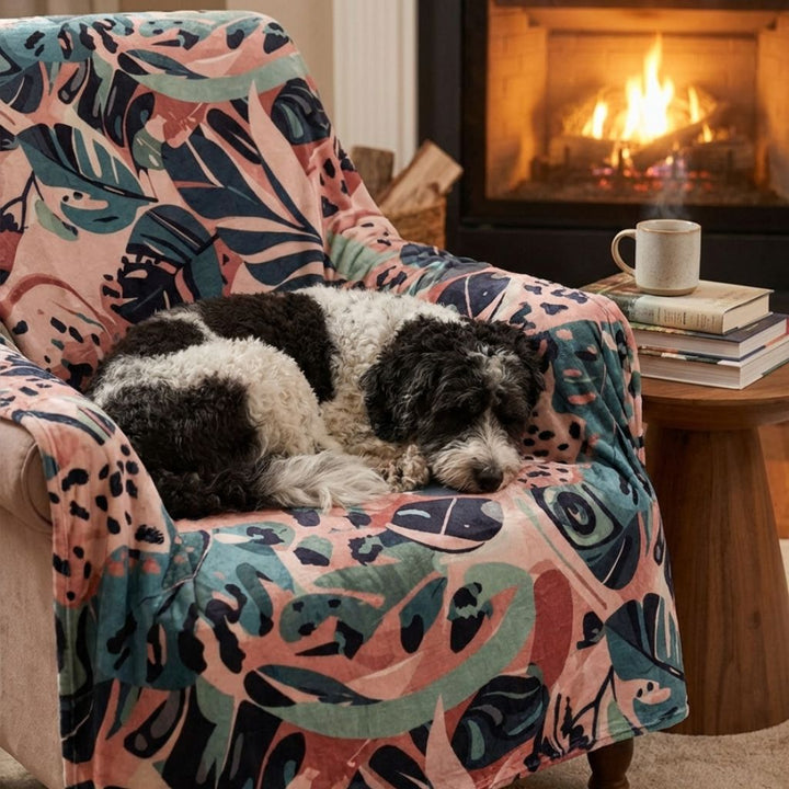 Un chien noir et blanc repose sur un fauteuil couvert d’un plaid Savane, tout près du feu de cheminée.